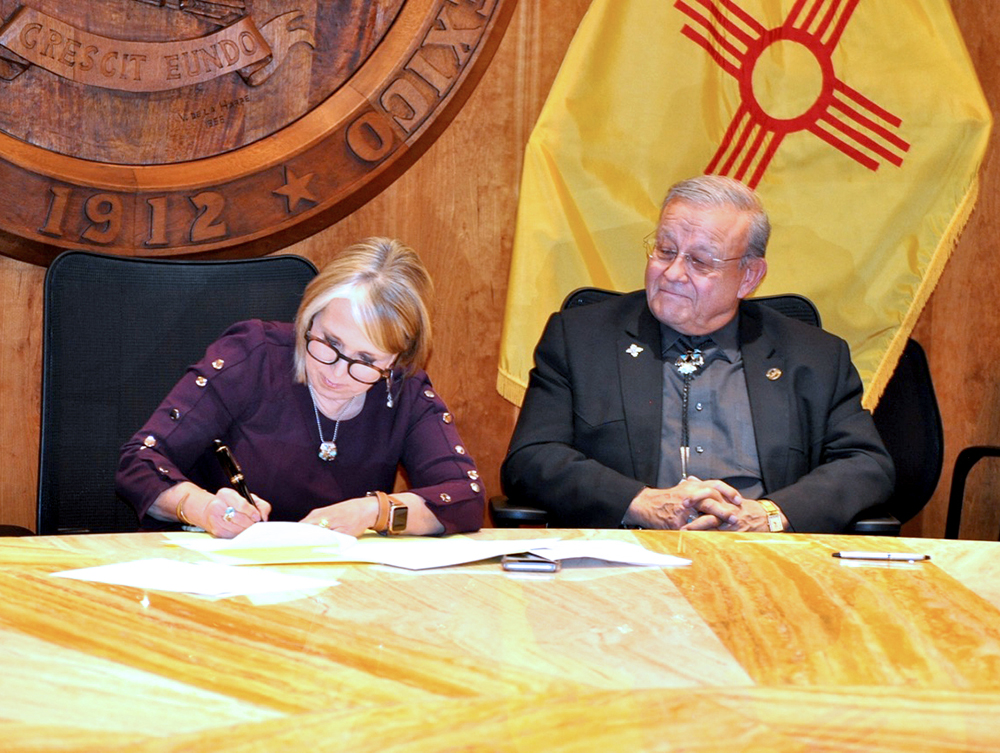 House Bill 44 sponsor Rep. Tomas Salazar looks on as Governor Michelle Lujan Grisham signs the Work and Save Act into law.